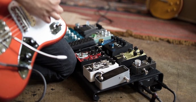 Electric Guitar Player Next to a Pedalboard