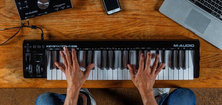 Man Playing a 49-key Keyboard Controller